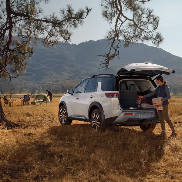 a woman loading a white Nissan Pathfinder in the outdoors