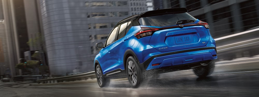 2024 Nissan Kicks in blue driving on wet city streets illustrating performance